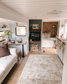 a living room filled with furniture and a fire place next to a kitchen area covered in wood