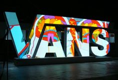 a large sign that says vans on it in front of a dark room with lights