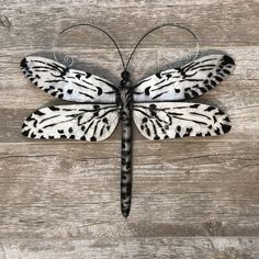 a white and black butterfly sitting on top of a wooden floor