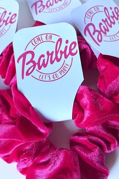 some pink scrunffles are laying on top of each other with the name barbie on them