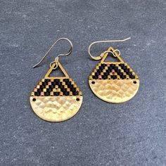 These brick stitch and brass beaded earrings were handwoven with Miyuki glass seed beads. A time intensive and intricate craft, each bead is carefully hand stitched in order to create an even, uniform weave. The process requires focus, patience and dedication, as even a small pair of earrings can take hours to complete. The tiny glass seed beads are incredibly lightweight, so even the larger size statement earrings can be comfortably worn all day long.  Handwoven Brick Stitch Beadwork Miyuki glass seed beads (Glass and 24k gold plated)  14k gold filled ear wires  Hammered raw brass half moon piece Brass triangle component Extra durable nylon beading thread Each bead is approx. 1.6mm x 1.3mm Size: 1 1/4" long (including ear wire), 3/4" wide Weight: 1g each (2g/pair) Handwoven Dangle Brass Earrings, Handwoven Brass Dangle Earrings, Gold Teardrop Earrings With Tiny Beads, Gold Teardrop Beaded Earrings With Tiny Beads, Handwoven Brass Beaded Dangle Earrings, Handwoven Brass Earrings For Gift, Gold Woven Dangle Earrings, Adjustable Handwoven Brass Earrings, Artisan Brass Jewelry With Tiny Beads