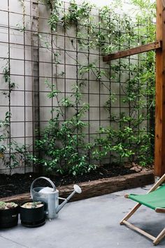 an outdoor patio with a chair, watering can and potted plants on the ground