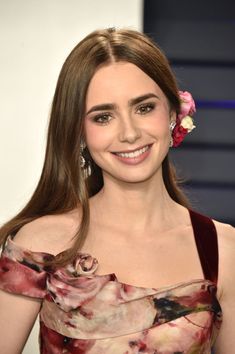 a woman in a floral dress smiling at the camera