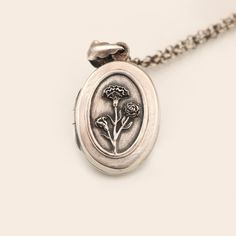 "Birth month flower locket necklace in 925 sterling silver with a working compass inside and a place for your favorite photo. One of January's birth flower is a carnation.  Depending on its color carnations can indicate many nuances of love, like a mother's love, admiration, remembrance, or deep unyielding love. Those born in January are thoughtful and wise in all matters of the heart. This lovely sterling silver oval locket features a lovely group of carnations on the front. The locket has been Engraved Sterling Silver Locket Necklace For Mom, Sterling Silver Locket Necklace Gift For Mom, Sterling Silver Locket Necklace For Mom, Silver Locket Necklace With Birth Flower Round Pendant, Sterling Silver Flower Pendant Necklace For Memorial, Silver Locket Necklace With Flower Charm As Gift, Sterling Silver Locket Necklace With Vintage Charm, Sterling Silver Vintage Charm Pendant Locket, Vintage Silver Birth Flower Necklace