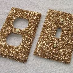 two gold glittered switchplate covers on a white surface