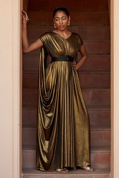 Antique gold draped gown with double pleated shoulder. Paired with embroidered elastic belt.
Component: 2
Pattern: Embroidery
Type Of Work: Glass bead, crystal
Neckline: V neck
Sleeve Type: Flared sleeves
Fabric: Lycra
Color: Gold
Other Details: 
Double pleats detailing
Elasticated belt
Occasion: Cocktail - Aza Fashions Drape Gown, Gold Drapes, Draped Gown, Gown Gold, Drape Gowns, Gown For Women, Embroidered Belt, Islamic Dress, Gown Pattern