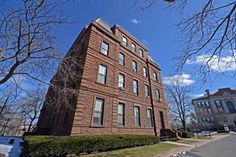 a tall brick building sitting on the side of a road next to trees and bushes