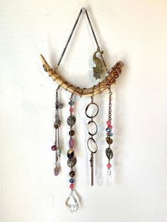 a wall hanging made out of wood with beads and charms attached to the back of it