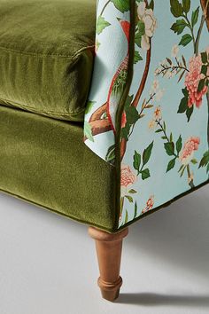 an upholstered green chair with floral print on the armrests and back