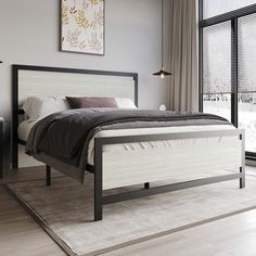 a white bed sitting next to a window in a room with wooden floors and large windows