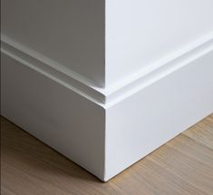 the corner of a white wall with wood flooring