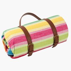 a multicolored striped blanket with brown leather straps on the bottom and inside, sitting on a white surface