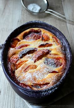 a baked dish with powdered sugar on top and spoon next to it, sitting on a wooden table