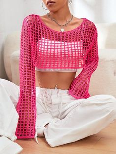 a woman sitting on the floor in white pants and a pink crop top with long sleeves