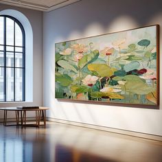 a large painting hanging on the wall next to a table in an empty room with big windows