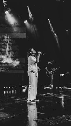 a woman standing on top of a stage holding a microphone in her hand and singing