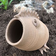 a clay vase sitting on the ground with dirt around it