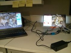 two laptop computers sitting on top of a white counter next to wires and plugs