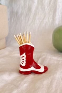 a pair of red boots with toothpicks sticking out of them on a bed