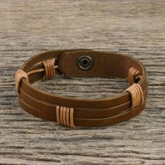 Chaloemphon of Thailand presents this men's leather wristband bracelet. The light brown leather has three horizontal slits. The artisan has wrapped two sections in black leather cord in artful intervals adding to the bracelet's texture and visual impact. The bracelet closes with a brass snap. Adjustable Leather Wristband With Waxed Finish, Adjustable Brown Leather Sweatband Wristband, Adjustable Brown Leather Wristband, Adjustable Distressed Brown Leather Bracelet, Brown Leather Bracelet With Waxed Finish, Adjustable Rugged Leather Bracelet, Brown Leather Wrap Bracelet For Gift, Brown Leather Wrap Bracelet Gift, Brown Leather Wrap Bracelet As Gift