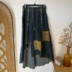 an old skirt hanging on the wall next to a wicker chair and vase with flowers