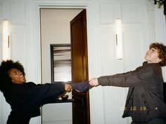 two people standing in front of a door and one is holding onto the other's tie