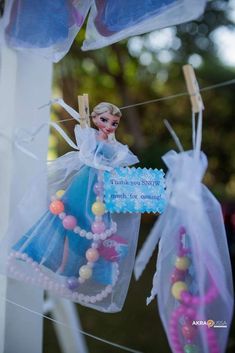 there is a doll hanging on the clothes line with some beads in front of it