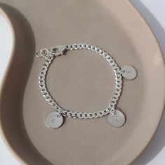 925 sterling silver Carter Personalized disc Bracelet laid on a gray plate in the sunlight. This bracelet features the Carter chain then followed Initial stamped disc. Sterling Silver Initials Bracelet For Personalized Gift, Minimalist Sterling Silver Name Bracelet For Personalized Gift, Minimalist Sterling Silver Name Bracelet As Personalized Gift, Personalized Sterling Silver Initials Bracelet, Dainty Customizable Silver Bracelet, Personalized Silver Charm Bracelet With Initials, Personalized Silver Bracelets With Initials, Personalized Silver Bracelet With Initials, Customizable Silver Charm Bracelet