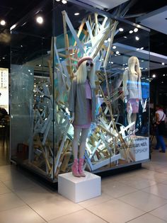 a woman standing in front of a display case with mannequins on it