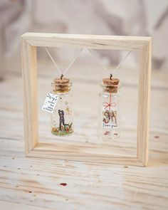 two miniature bottles with pictures in them sitting on a table next to a wooden frame