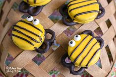 four decorated cookies in the shape of bees with googly eyes and chocolate on them