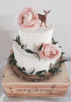 a three tiered cake with pink flowers and a deer figurine on top