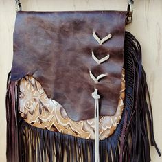 Channel the spirit of the Southwest with this boho handbag from Jewelry Junkie! Featuring a bold, Chateau print, this crossbody bag is sure to leave an impression. Made from genuine leather Fully lined Zipper closure Comes with a matching crossbody leather strap 36" long Measures 10” x 9” with a 10” leather fringe Genuine leather flap with raw cowhide edge Suede Lacing on the front of the flap Handmade and sourced in Texas, so no two bags are ever identical Embossed pattern evokes images of the Leather Hobo Bag Crossbody For Festival, Leather Satchel Bag With Fringe, Leather Crossbody Hobo Bag For Festivals, Bohemian Leather Saddle Bag With Leather Handles, Leather Fringe Pouch Bag, Bohemian Leather Shoulder Bag With Leather Handles, Artisan Leather Shoulder Bag For Festival, Brown Festival Bag With Removable Pouch, Handmade Bohemian Leather Saddle Bag