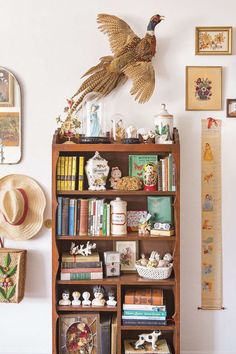 a bookshelf filled with lots of books next to a wall mounted pheasant