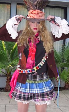 a woman in a skirt and top hat with her hands on her head, posing for the camera