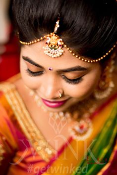 a woman in a yellow and green sari with gold jewelry on her head, looking down