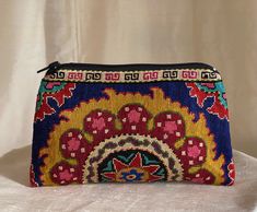 "Small Silk Petit Point Clutch, Handbag Organizer, Make Up Organizer created and handmade in Uzbekistan. Lined with silk and cotton fabric, zipper top.  Each clutch is hand drawn on to cotton canvas, inspired by original designs from Uzbekistan history.  Measures 6\"  high x 10\" width, 7\" opening  Embroidery the same on the front and the back of the clutch Can fit largest sizes of iPhone and Android. 100% silk petit point with handwoven silk and cotton lining. Your purchase preserves and encou Bohemian Multicolor Clutch With Zipper Pouch, Artisan Multicolor Rectangular Clutch, Bohemian Multicolor Clutch Pouch, Traditional Multicolor Shoulder Bag With Removable Pouch, Blue Bohemian Rectangular Pouch, Bohemian Multicolor Coin Purse For Daily Use, Handmade Multicolor Coin Purse For Travel, Traditional Multicolor Bag With Zipper Pouch, Daily Use Bohemian Coin Purse