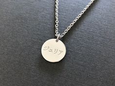 This is for a personalized engraved Japanese name necklace of your choice from the metal: gold plated brass or gold plated sterling silver. The sterling silver base jewelry is nickel free. The white gold plated sample necklace is engraved with a name Julia in Japanese in the font #2. One side or both sides, front & back can be engraved in Japanese and numbers. Please check the font options in the pictures. The sample pendant is 1.5 cm (0.6 inches) wide. The available 2 pendant sizes are 1.5 cm ( Silver Engraved Text Pendant Necklace, Silver Pendant Necklace With Engraved Text, Customizable Silver Necklace With Round Pendant, Silver Custom Necklace With Round Pendant, Sterling Silver Pendant Name Necklace With Engraving, Silver Sterling Name Necklace With Engraving Option, Sterling Silver Name Necklace With Engraving Option, Sterling Silver Pendant Necklace With Engraved Text, Silver Engraved Pendant Necklace