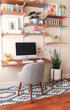 a desk with a computer on top of it next to a potted snake plant