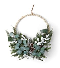 a wreath with greenery and pine cones hanging on a wall ornament for decoration