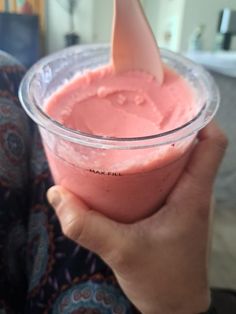 a person holding a plastic cup filled with pink liquid