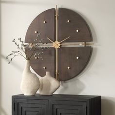 two vases sitting on top of a black cabinet in front of a large clock