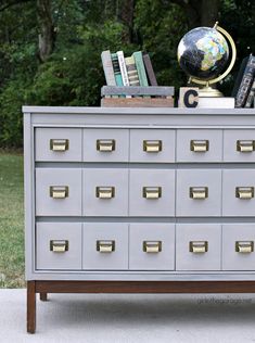 a gray dresser with many drawers and books on top