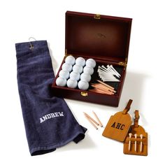 an open case with golf balls and tees in it next to a towel, tags and other items