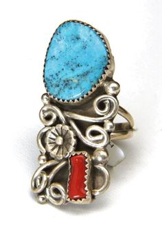 Handmade Navajo Turquoise and Coral Ring!-Artisan Kenneth Jones beautifully made ring-Large bright blue turquoise stone and deep red coral piece adorn this ring-Intricate silver work with curls, small bubbles, and a pretty central flower-Ring is marked "Sterling" "K", sticker tag states artist name and ring information-Ring face measures 1.7" x .75"-Turquoise stone measures about 18mm x 15mm, coral stone measures 10mm x 4mm-Depth of ring .23"-Size 7.5-Total weight 10.6g-Ring is in excellent cond Collectible Blue Multi-stone Turquoise Ring, Collectible Blue Turquoise Inlay Ring, Southwestern Style Turquoise Inlay Ring, Bohemian Untreated Blue Turquoise Ring, Collectible Multi-stone Blue Turquoise Ring, Southwestern Style Untreated Blue Turquoise Ring, Unique Blue Turquoise Ring With Inlay, Handmade Blue Turquoise Ring For Collectors, Southwestern Blue Jewelry With Large Stone