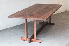 a wooden table sitting on top of a cement floor next to a white brick wall