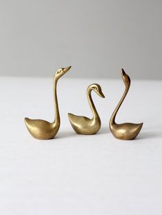 two brass swan figurines sitting next to each other