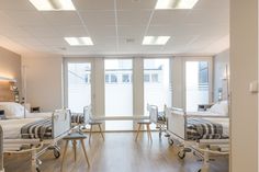 an empty hospital room with multiple beds and chairs