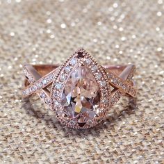 a pink diamond ring sitting on top of a tan cloth covered floor with sparkles in the background