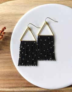 These earrings have an elegant feel with their matte black finish and gold beads speckled throughout. Beading hangs from a beautiful gold plated triangular form with 14K gold plated hypoallergenic ear wires. **Each of my earrings are delicately handwoven bead by bead. I absolutely love making these and want you to know that each piece is made with patience and care from start to finish! These earrings are made with size 11/0 Delica Japanese Miyuki seed beads. I use strong nylon thread to ensure Elegant Black Beaded Earrings With Tiny Beads, Elegant Black Earrings With Tiny Beads, Black Beaded Dangle Earrings With Beaded Chain, Black Beaded Chain Dangle Earrings, Black Beaded Chain Earrings As A Gift, Elegant Black Beaded Earrings With Gold Beads, Black Beaded Drop Earrings With Gold Beads, Black And Gold Beaded Drop Earrings, Black Earrings With Gold Beads As Gift